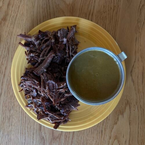 Shredded chuck roast in a Dutch oven with a rich orange-poblano braising sauce